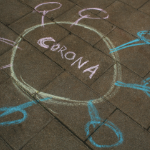 一幅用彩色粉笔画在砖砌人行道上的新冠病毒漫画