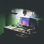 在黑暗的房间里，一盏台灯照亮了一台电脑和凌乱的桌子