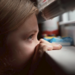 一个年轻的女孩偷看一个窗外