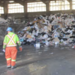 在奥特湖垃圾场的仓库里，一个人站在堆积如山的垃圾前