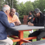 Gary Burrill, Colter Simmonds和Quentrel Provo坐在户外的一张桌子旁聊天