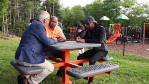 NDP领导Gary Burrill，NDP Preston候选人Colter Simmonds和社区Activist Quentrel Provo聊天在野餐桌上。