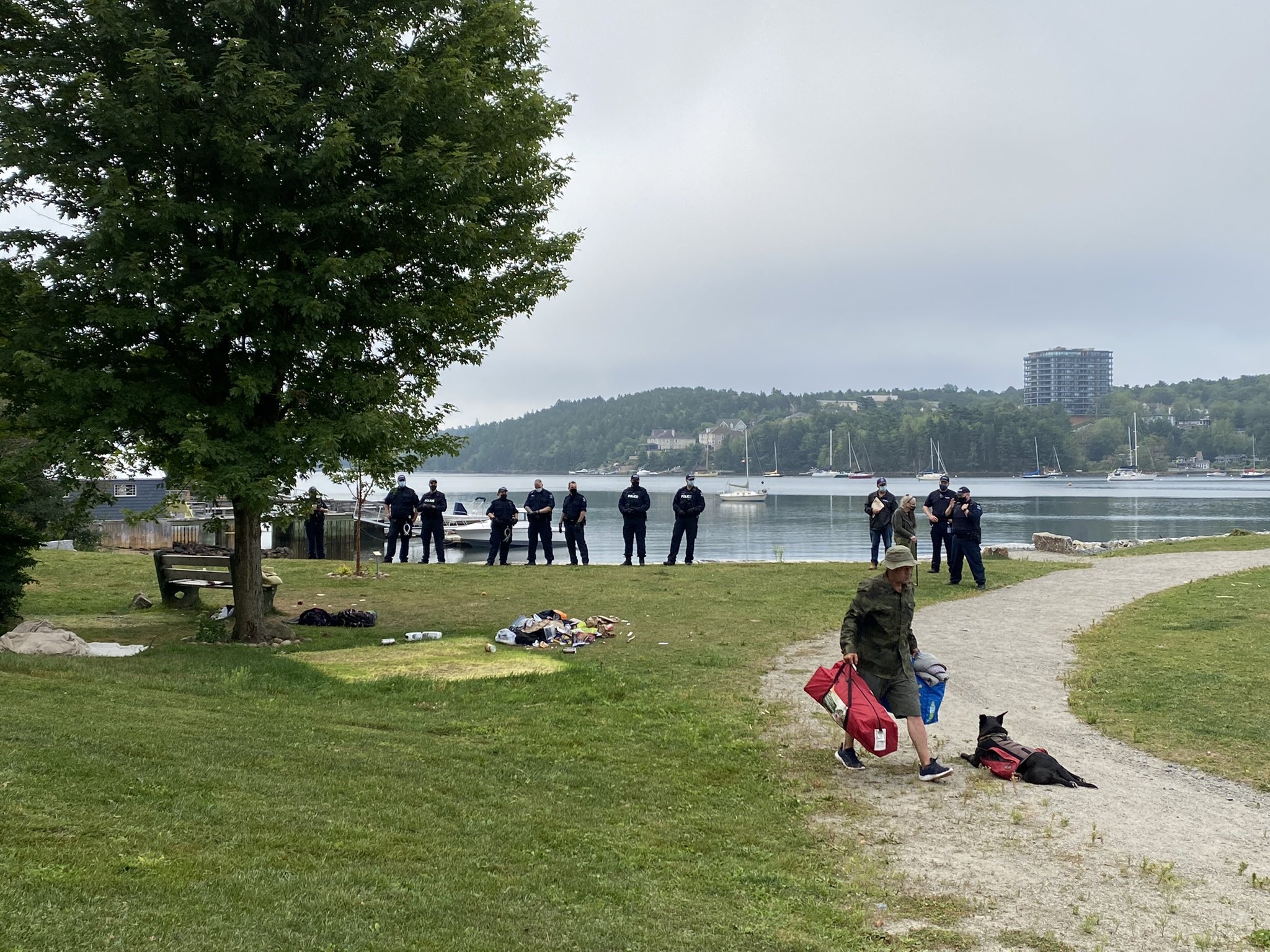 公园有海洋在背景中。一条线在背景中站立，当一个人走开时，拿着一个帐篷。