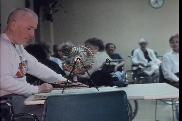 蒙特利尔Canadiens衬衣的人拜访宾果游戏在一个机构室有佩带医院褂子的机构室在背景中