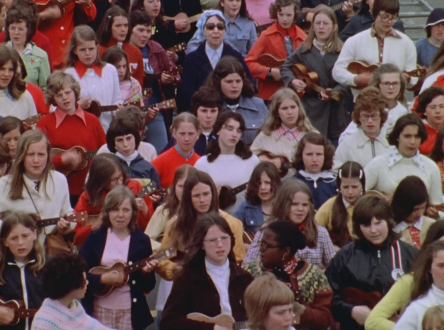 一大群孩子在户外站得很近，演奏四弦琴。这张照片拍摄于20世纪70年代，衣服的年代与照片相同。