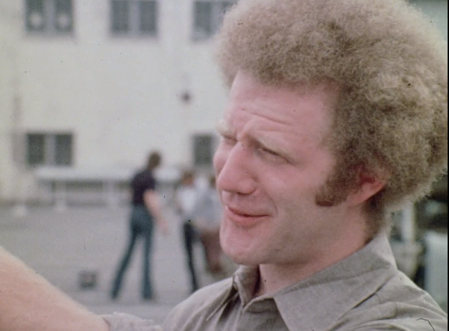 一头卷发的男人微笑着。