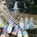 Empty dish soap bottles lined up in front of a pristine waterfall.