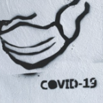 白色墙壁上的黑色模板和“COVID - 19”字样。