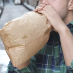 一个男人对着一个纸袋呼气