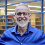 韦恩·麦凯，穿着宝蓝色衬衫微笑的布罗德利