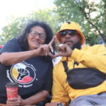 一个黑人和一个戴着丝带裙子的土着女人一起制作手势。