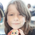 A ten-year-old girl holding a toy baby seal, smiling at the camera