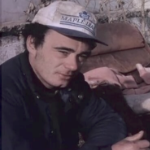 一个穿着球帽的男人坐在一些破碎的家具附近