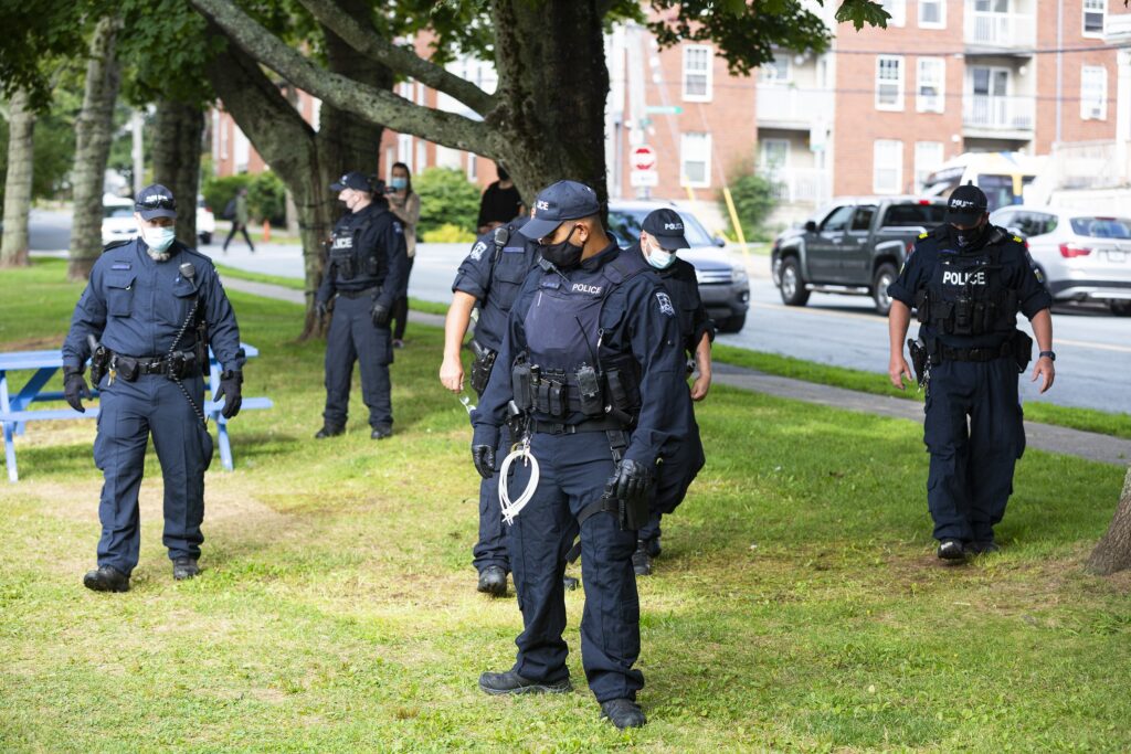 Several police officers standing in a park.