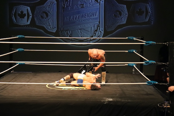 JP希姆斯双手握着一把椅子，俯身看着柯维·克里斯特，他似乎在痛苦地扭动着身体