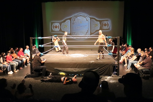 柯维·克里斯特跪在角落里，裁判站在场地中央，望着西姆斯，西姆斯望着场地外地板上的另一位裁判