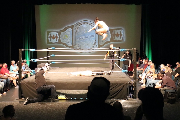 柯维·克里斯特抓住半空中，像炮弹一样，他跳到俯卧的JP·西姆斯身上。