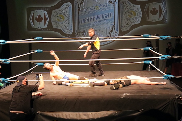 裁判指着柯维·克里斯特，他举起手臂，表现出精疲力竭的胜利。JP西姆斯仰面躺着，双臂张开。