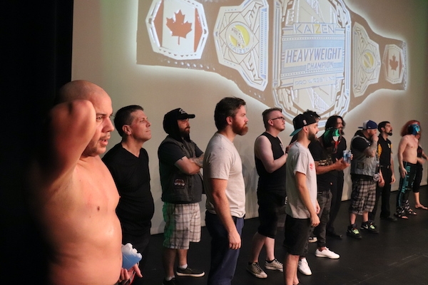 拳台外的一排男子，前景是光着膀子的JP希姆斯