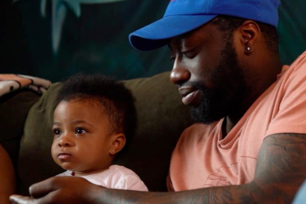 Kemmy Smith looks fondly at his little girl while they sit together on a sofa