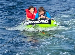 一张麦琪和扎克在水中的管子上被船拉着的照片。