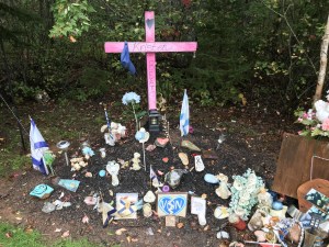 为2020年4月在新斯科舍省枪击案中丧生的克里斯汀·比顿建造的路边纪念碑。纪念碑是一个粉红色的十字架，周围是鲜花、照片、新斯科舍省旗帜和彩绘的岩石。