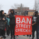Black Haligonians walk with a red banner that reads 