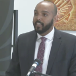 黑人男子布兰登·罗尔·罗勒，在讲台上讲一个麦克风。