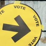 一个黄色的圆形投票标志，上面有一个黑色的大箭头