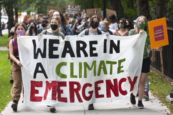 数百人在城市街道上游行，横幅上写着“我们正处于气候紧急状态”
