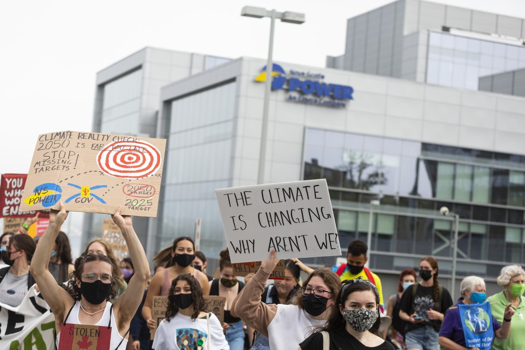 Protesters hold signs including one reading, 