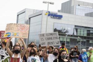 Protesters hold signs including one reading, 