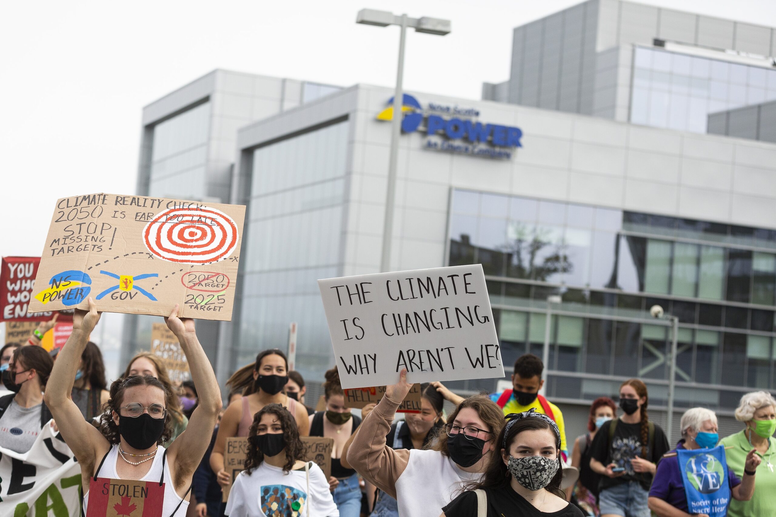 Protesters hold signs including one reading, 