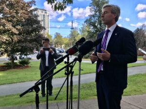 图为新斯科舍省省长蒂姆·休斯顿站在麦克风前发表关于新斯科舍省医疗保健的声明。