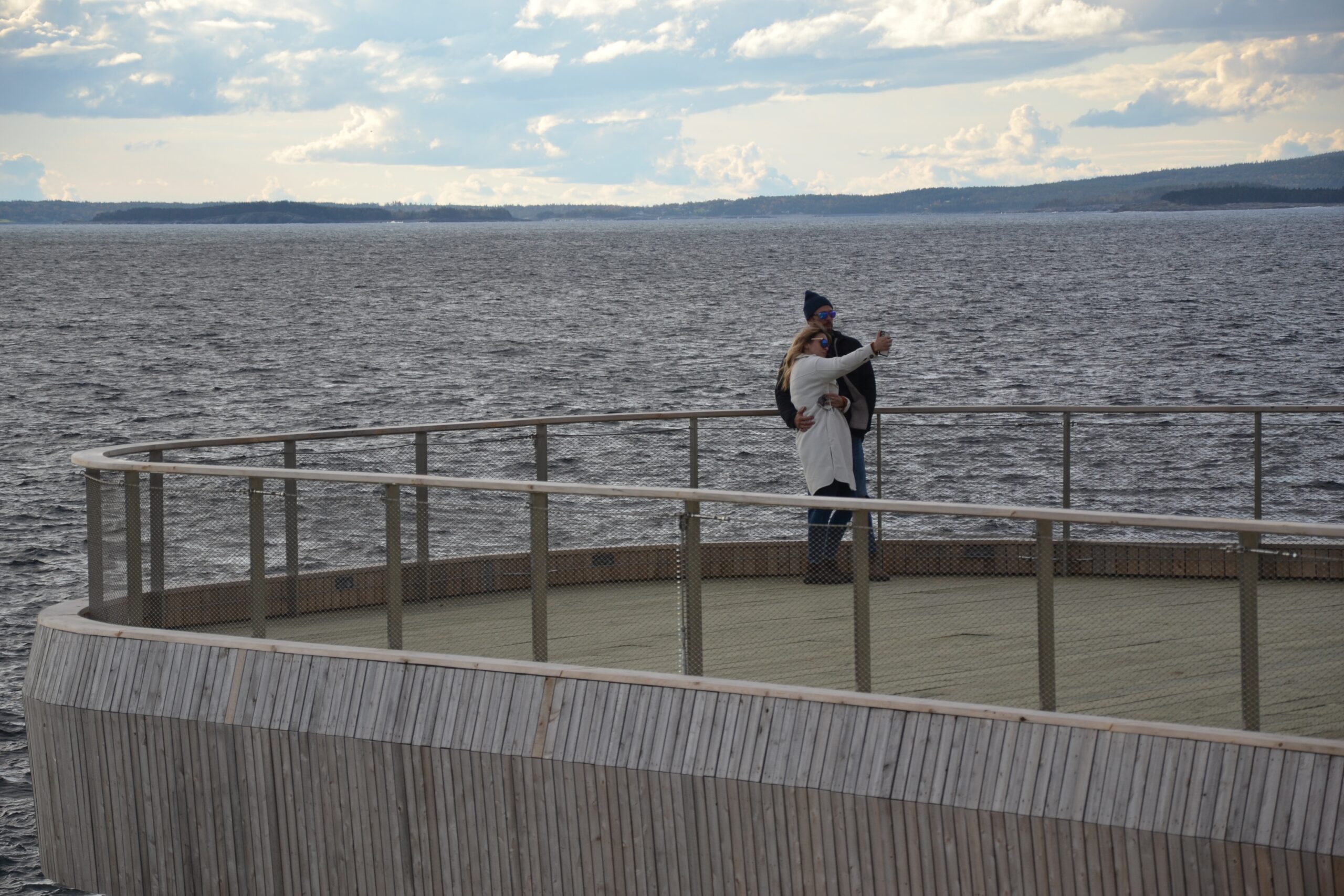 一对情侣在甲板上自拍，背景是大海。