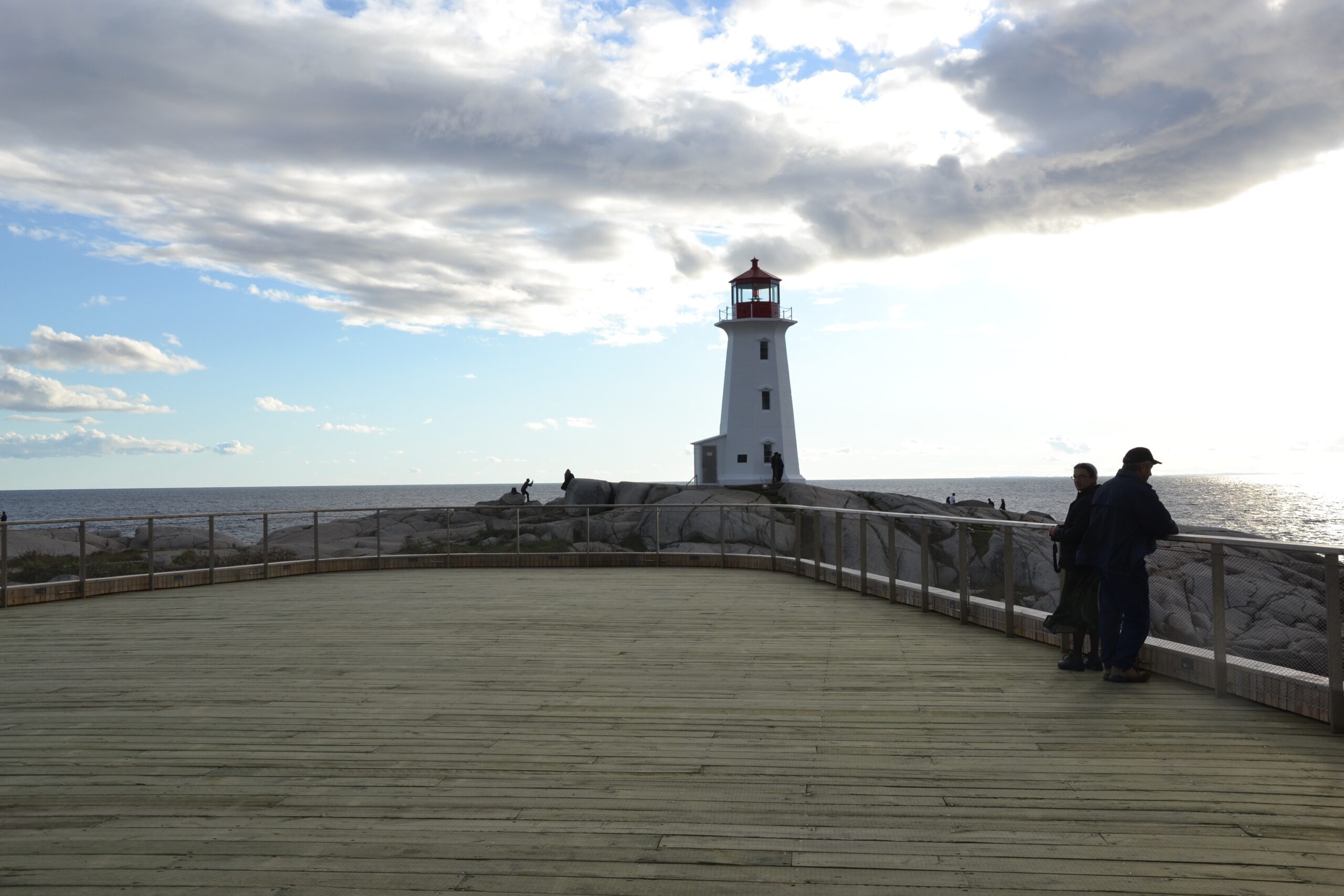 宽阔的木制观景台，远处有灯塔，头顶上有引人注目的云朵