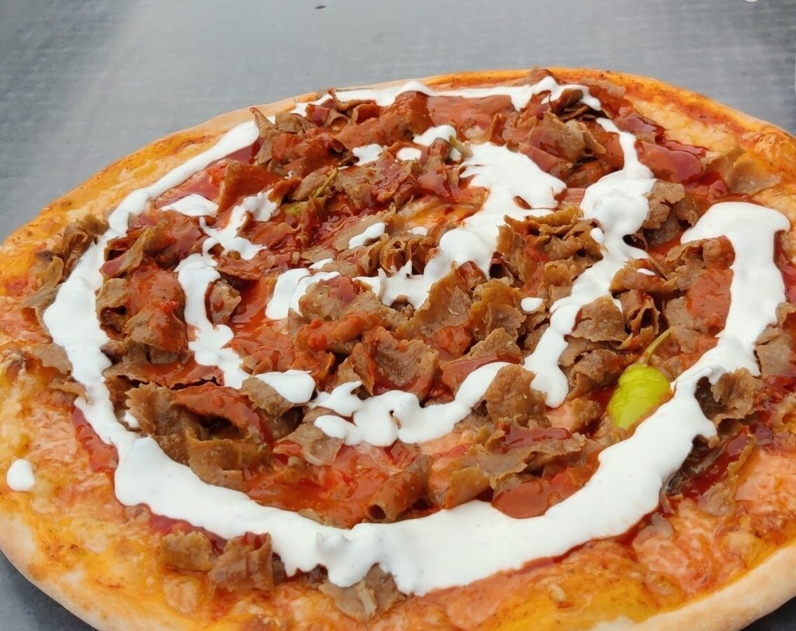 披萨上面有难以辨认的配料。也许是某种肉，上面有一圈厚厚的白色酱汁。