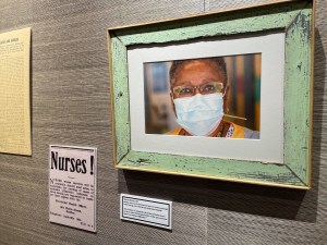 新斯科舍档案馆蔡斯画廊展出的一张照片显示，注册护士玛莎·布朗戴着一个蓝色的一次性口罩。布朗重新退休，帮助应对COVID大流行。她的照片是Len Wagg拍摄的一组照片中的一部分，他正在记录医护人员如何帮助应对COVID大流行。本次展览还包括来自新斯科舍省档案馆的剪报、照片和其他有关流行病的历史文件。这些物品陈列在墙上，和莱恩·瓦格的照片放在一起。