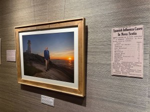 首席医疗官罗伯特·斯特朗博士站在佩吉斯湾的岩石上的照片。斯特朗的肖像是摄影师莱恩·瓦格(Len Wagg)展览的一部分，在新斯科舍省档案馆的蔡斯画廊展出。