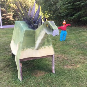 一个南瓜人站在一个临时的剑龙雕像旁边。