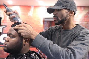 特里梅恩·豪(Tremayne“Trobiz”Howe)在他的“名人”理发店里为一位顾客理发。