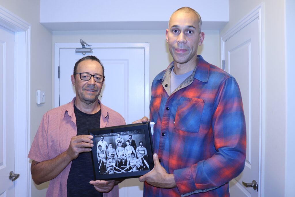 Paul Byard和Hubert Davis的照片。Byard在左边，Davis在右边。这两名男子手里拿着一张特鲁罗维多利亚曲棍球队的照片。