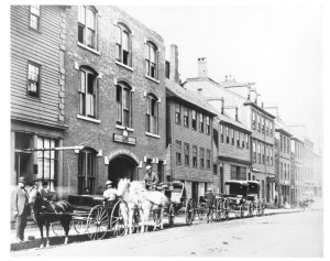 在哈利法克斯市中心的街道上，马和马车排成一列的黑白照片。