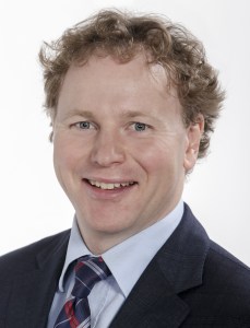 新斯科舍省财政和财政委员会部长艾伦·麦克马斯特的头像。麦克马斯特是个留着淡红色卷发的白人。他穿着深色西装，浅色衬衫，打着格子领带。(新斯科舍省通讯)