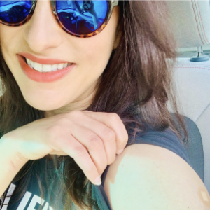 莎拉·莱利在一张自拍中微笑着拉起袖子展示她的疫苗创可贴