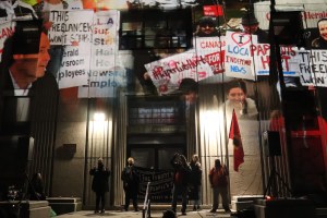 《新斯科舍省倡导者报》(Nova Scotia Advocate)的出版人兼编辑罗伯特·德维特(Robert Devet)的纪念照片，他于9月去世。这张照片显示的是抗议者将标语投射在位于春园路的旧图书馆前面的画面。有几个人站在图书馆的台阶上向人群讲话。