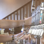 A shot of a male bartender's arms as he pulls pints