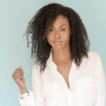 Vinessa Antoine, a young Black woman with shoulder length curly hair, against a blue green background