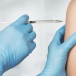 蓝色手套的手的特写镜头将注射到一个人的手臂上。