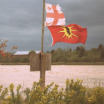 奥尔顿天然气基地的Shubenacadie河，有Mi'kmaq和勇士旗。你的天空黑暗而多云，河流是红色的。